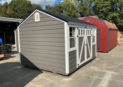Gray painted storage shed with black metal roof