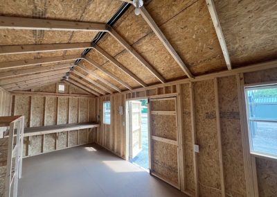 Interior of a utility shed with electric package, shelving, and workbench